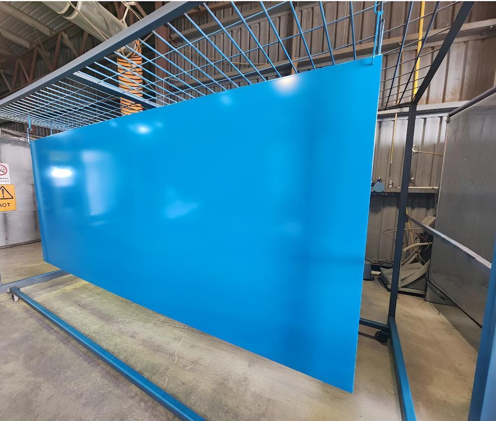 A Large Blue Piece Of Metal Is Sitting On Top Of A Metal Rack — ADK Coatings In Yeppoon, QLD