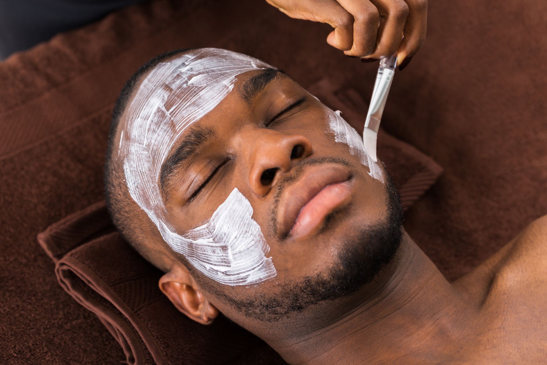 a man is getting a facial treatment with a brush