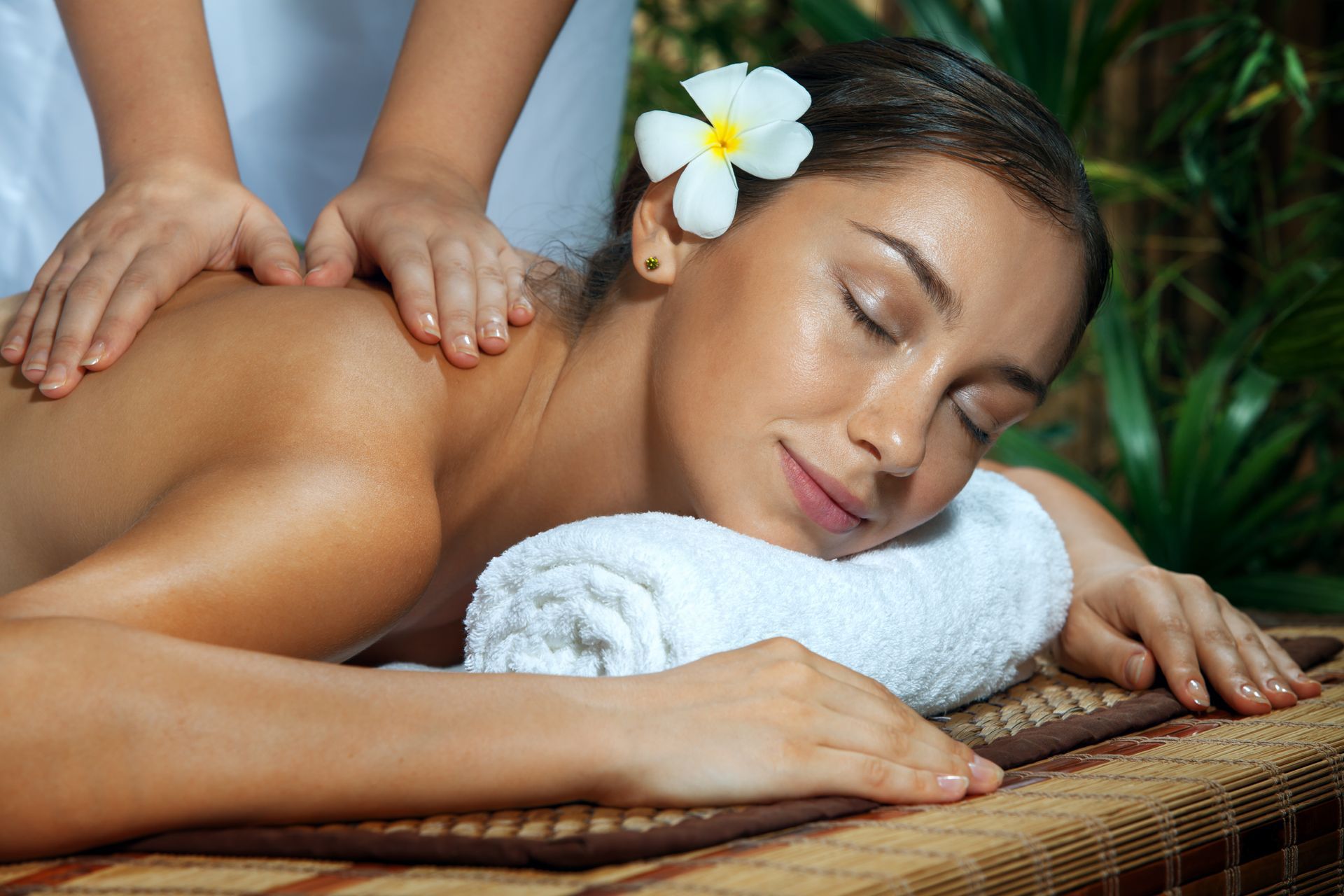 a woman is getting a massage with a flower in her hair
