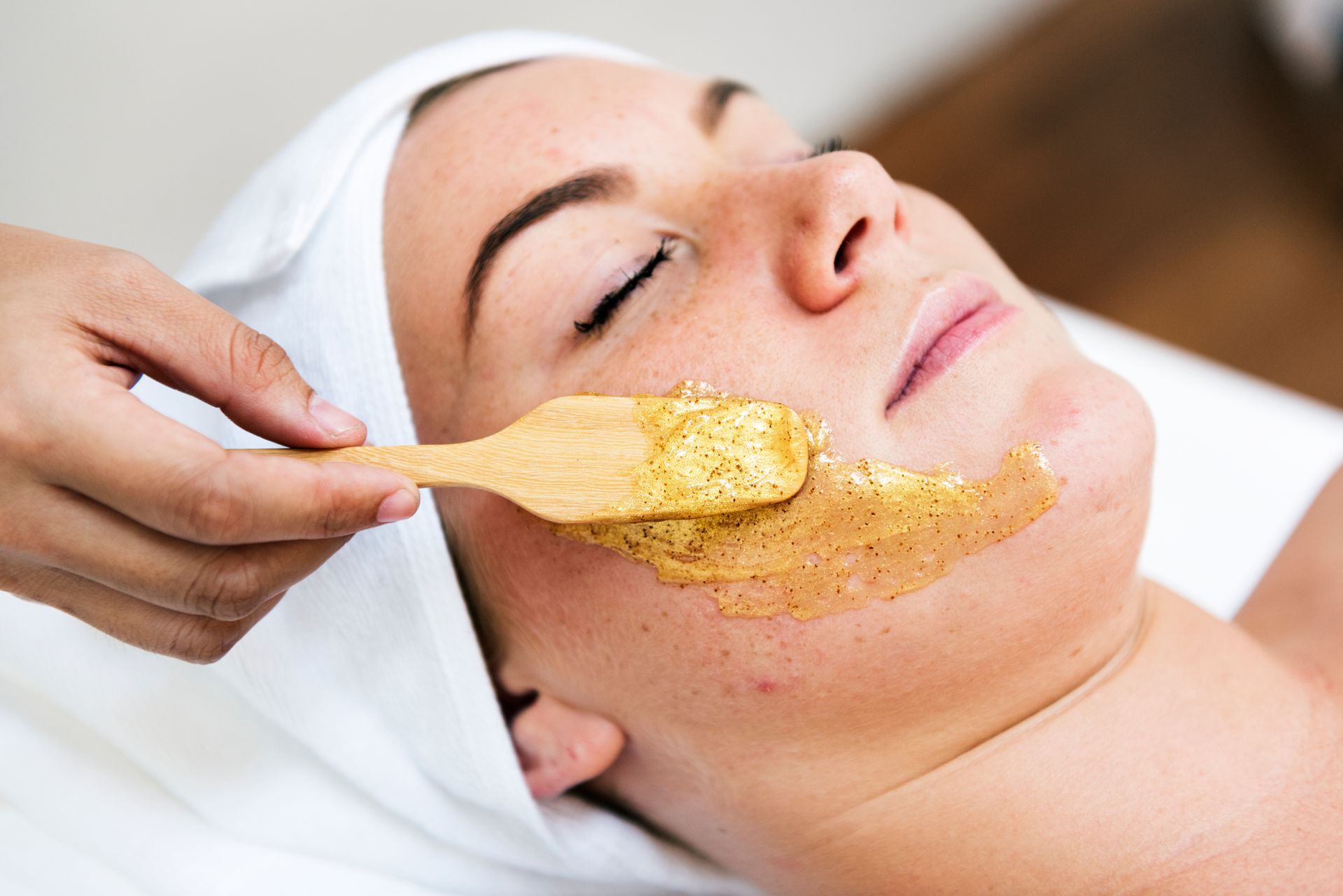 a woman is getting a facial treatment with a wooden spoon