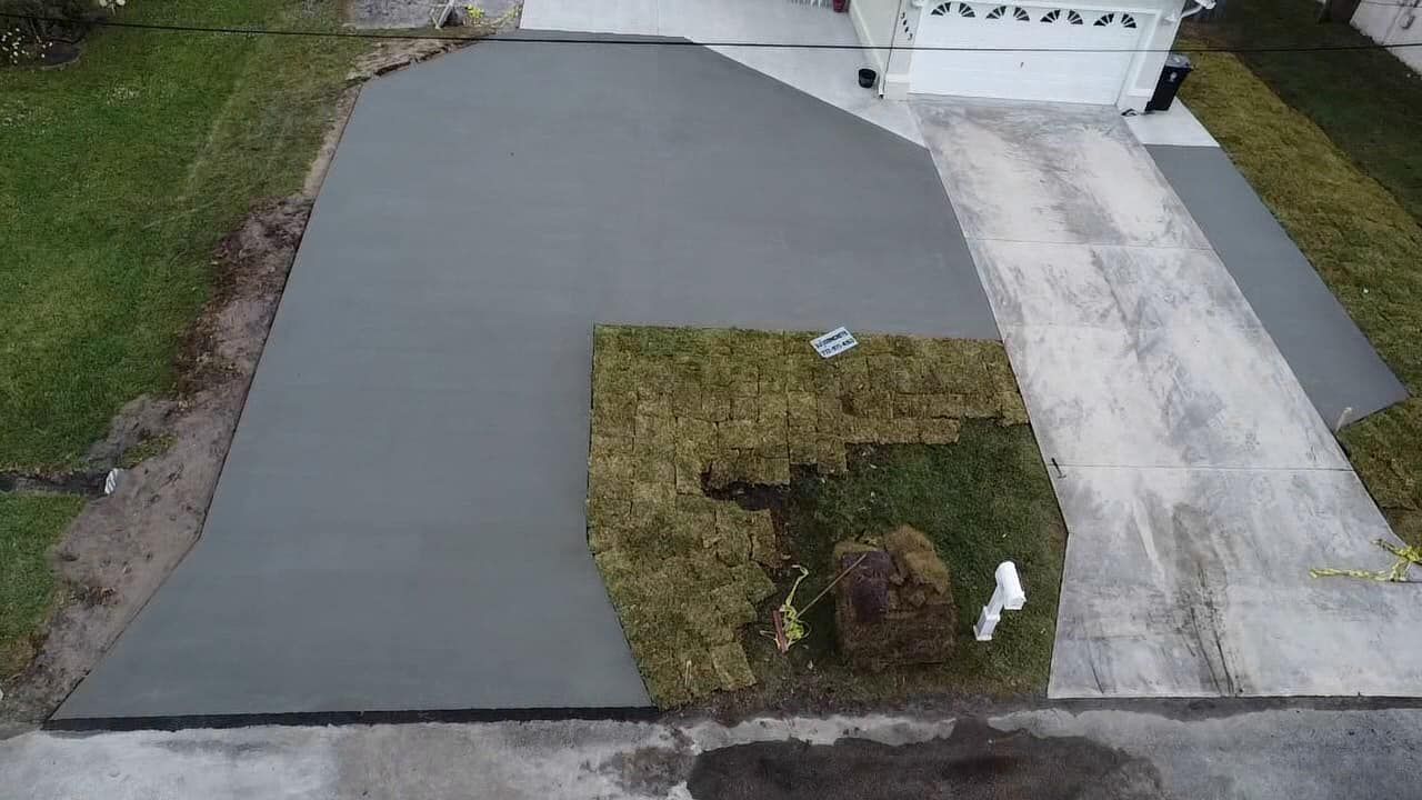 Newly poured concrete driveway with a patch of removed grass.