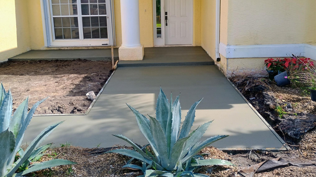 Freshly poured concrete walkway and steps leading to a house entrance.