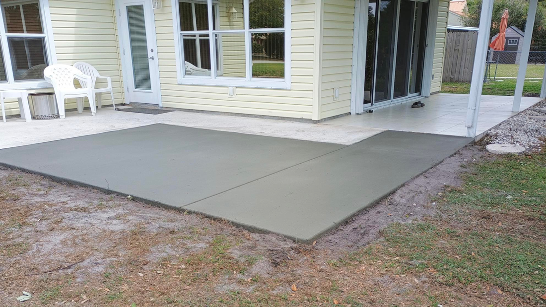 Gray patio foam tiles laid on concrete patio, near a house and yard.