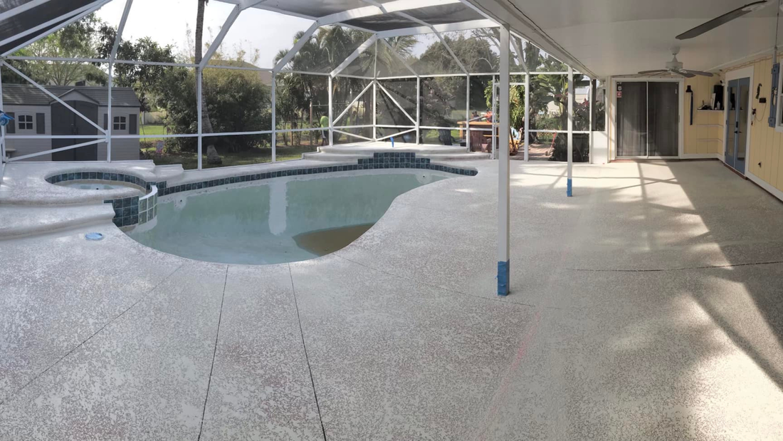 Pool area with pool, hot tub, and screened enclosure. Concrete floor, trees in background.