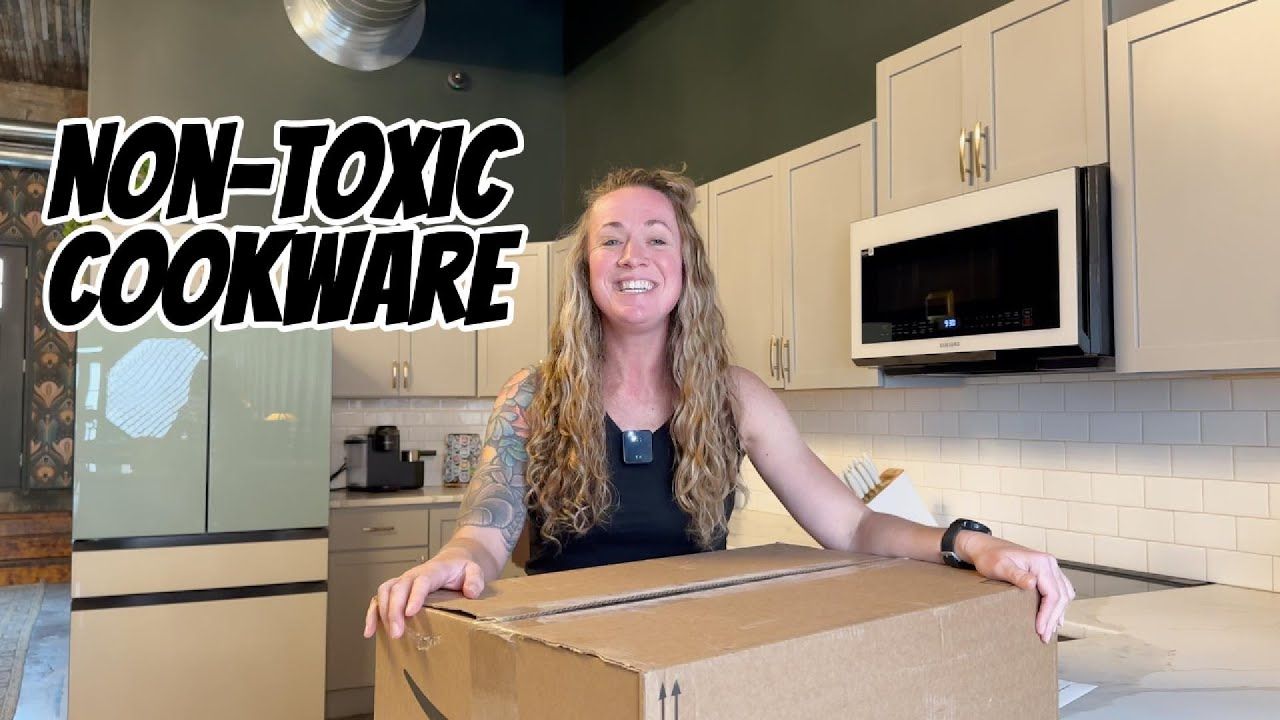 A woman is holding a cardboard box in a kitchen.