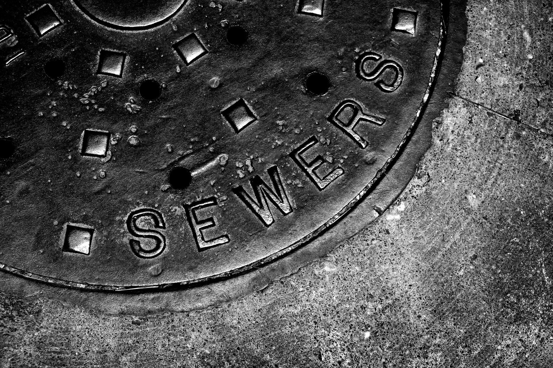 Close-up of a metal sewer manhole cover in black and white.