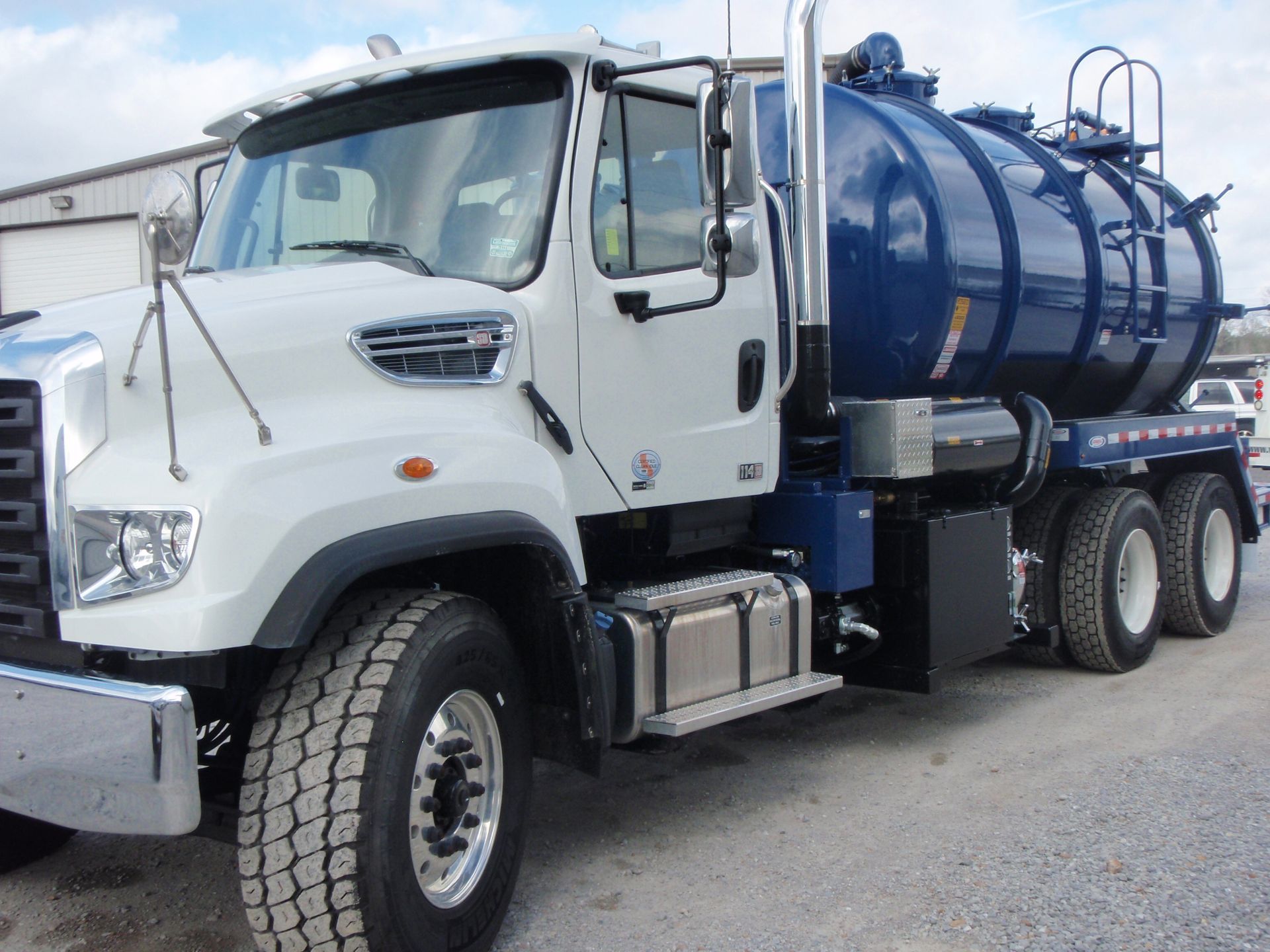 White and blue vacuum truck parked outdoors.