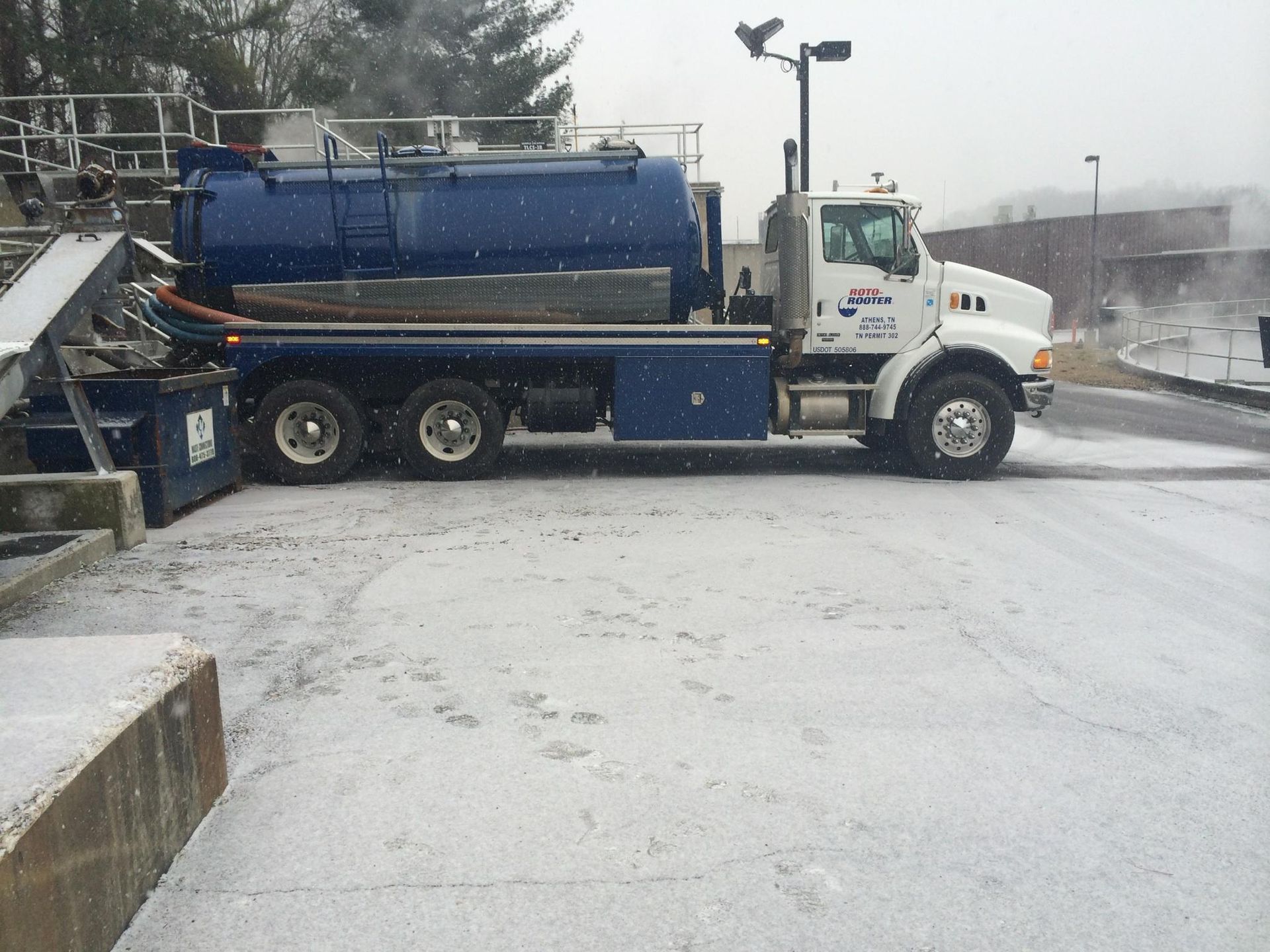 Blue vacuum truck parked in snowy conditions.