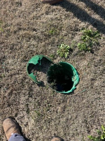 Green, broken plastic container in dry grass, outdoors.