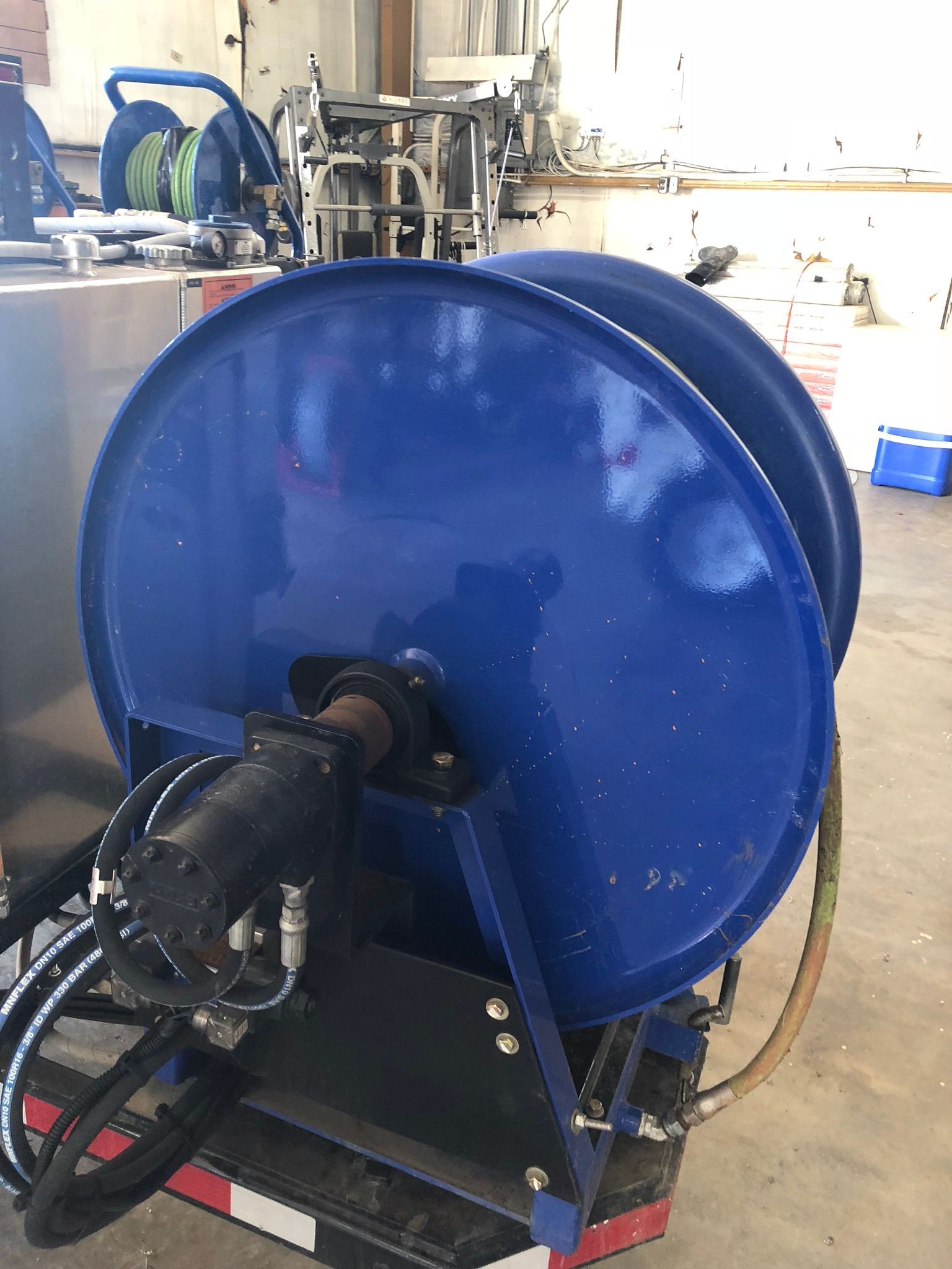 Blue hose reel, black motor, mounted on a metal frame, in a workshop.