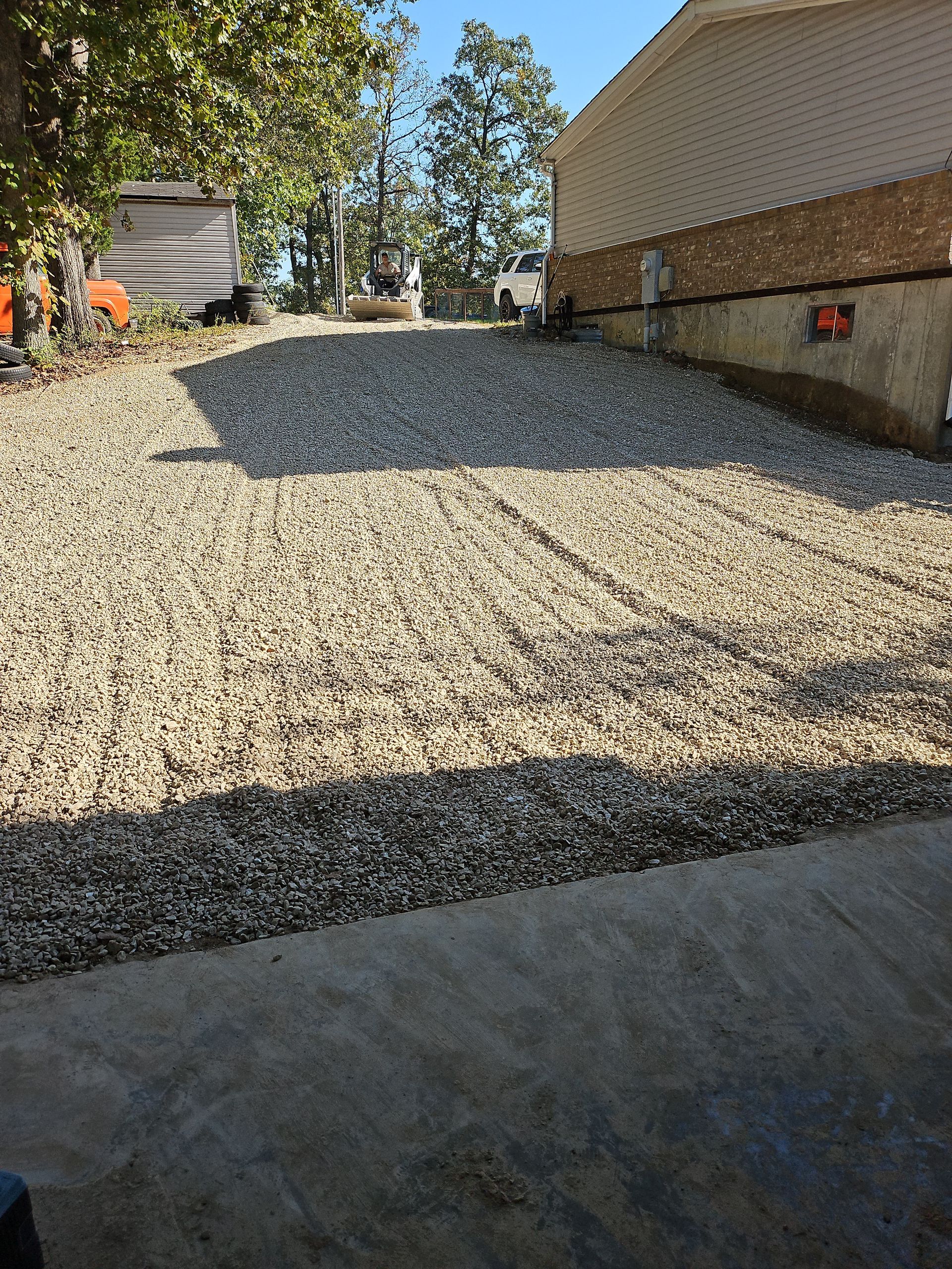 Gravel driveway leading up to a light tan building with a concrete entrance.