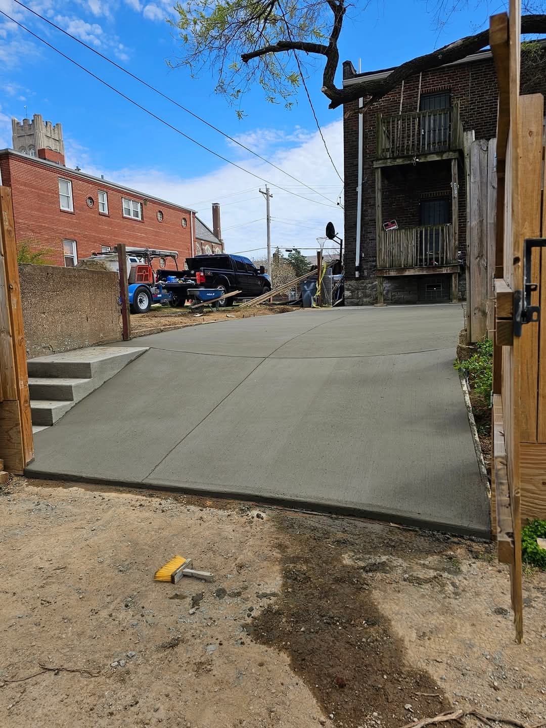 New concrete driveway with ramp and steps next to weathered wooden building, outdoors.