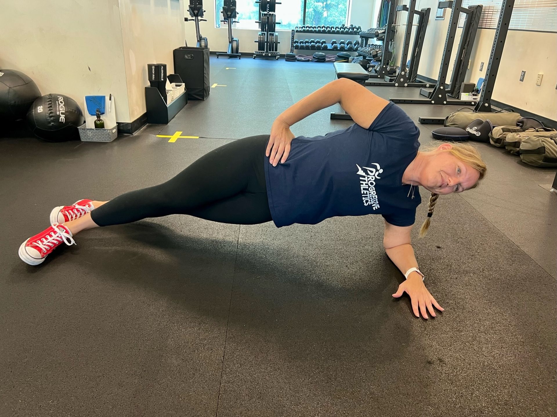 A woman is doing a side plank in a gym.