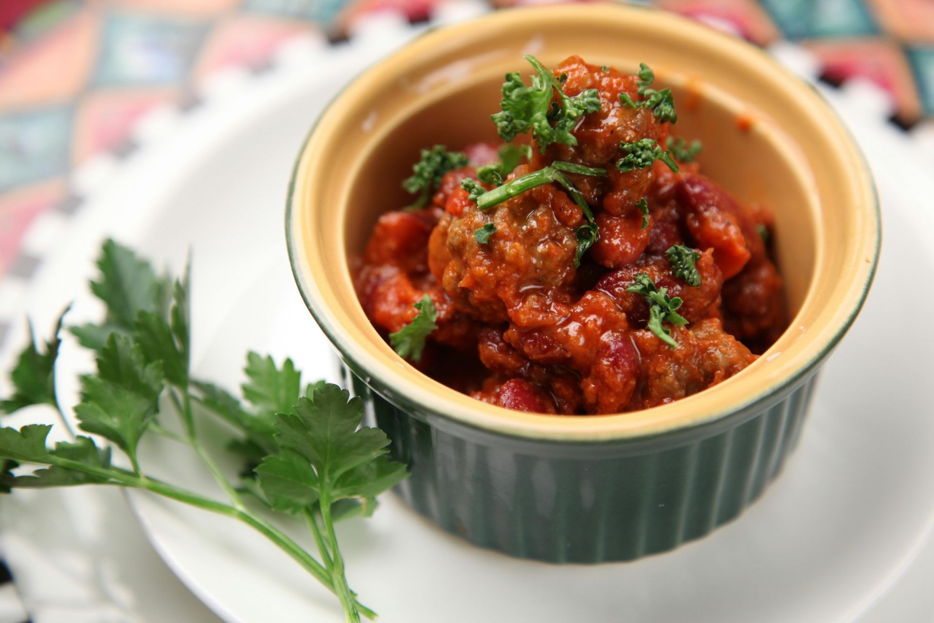 A bowl of chili with meat and beans garnished with parsley