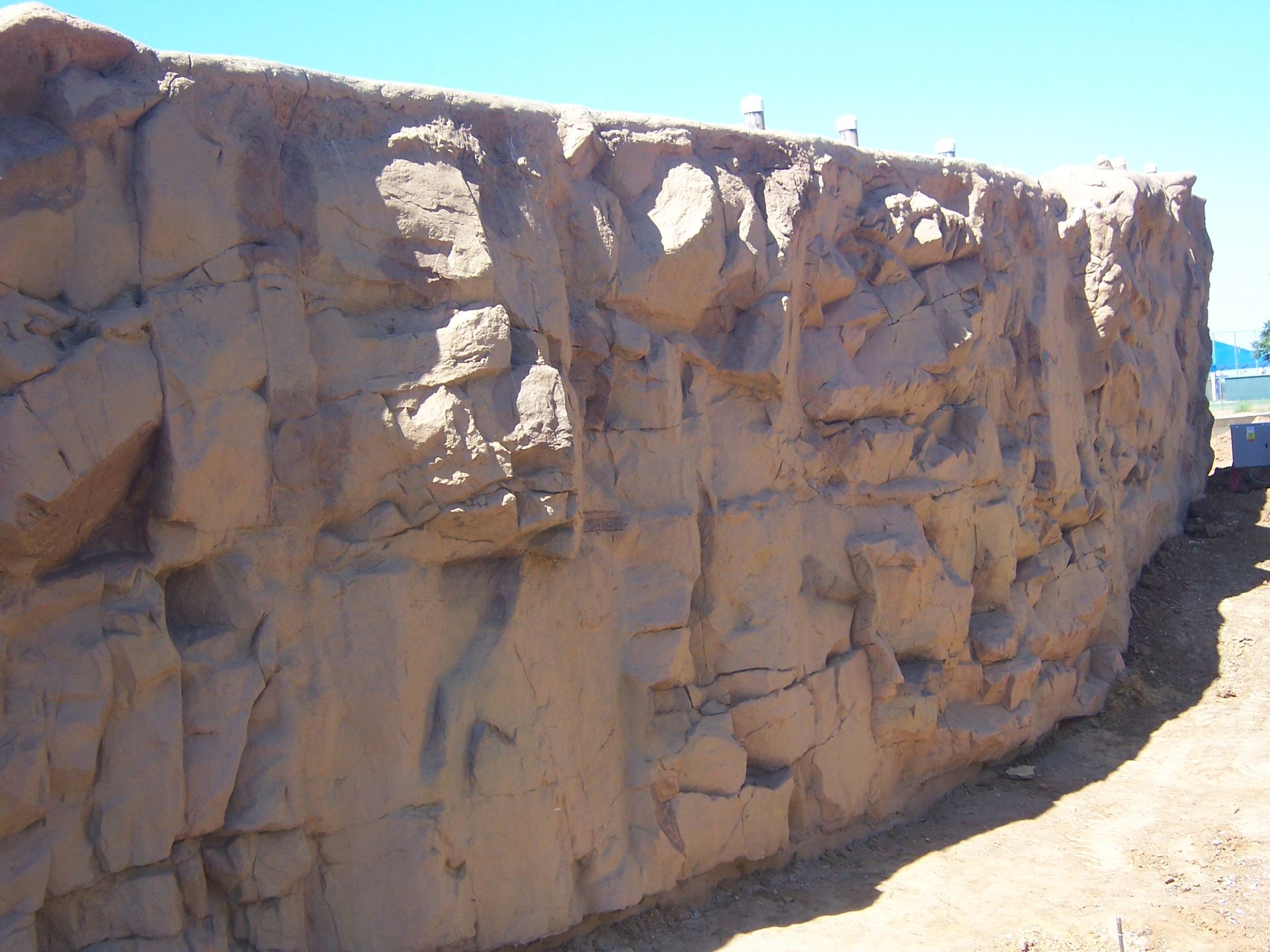 Tan, faux rock wall under a clear, blue sky.