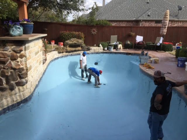 Person installing light-colored stone veneer on a wall, using both hands to position a tile.
