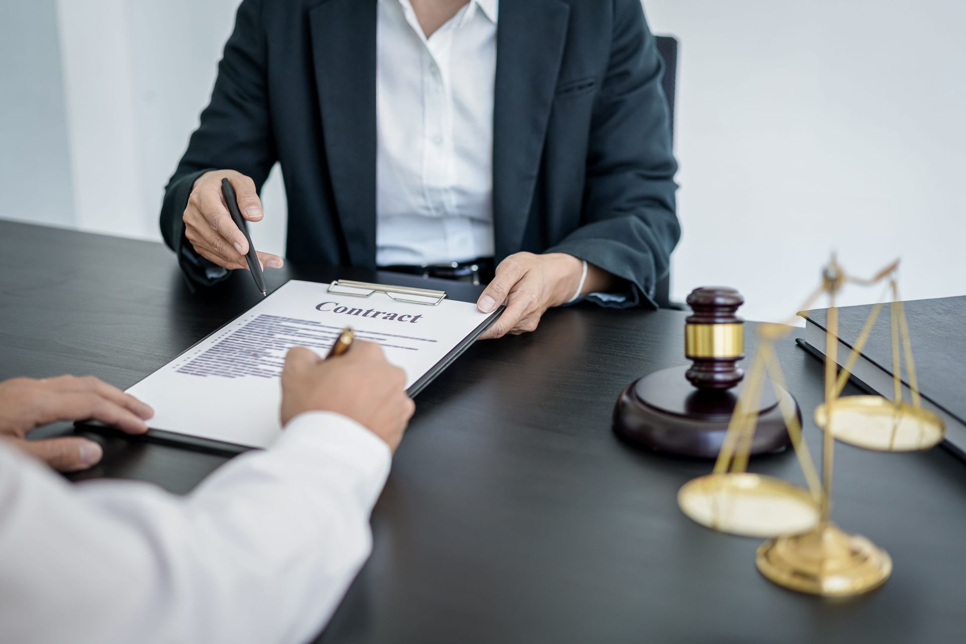 Lawyer and client reviewing a legal document with scales and gavel on a desk