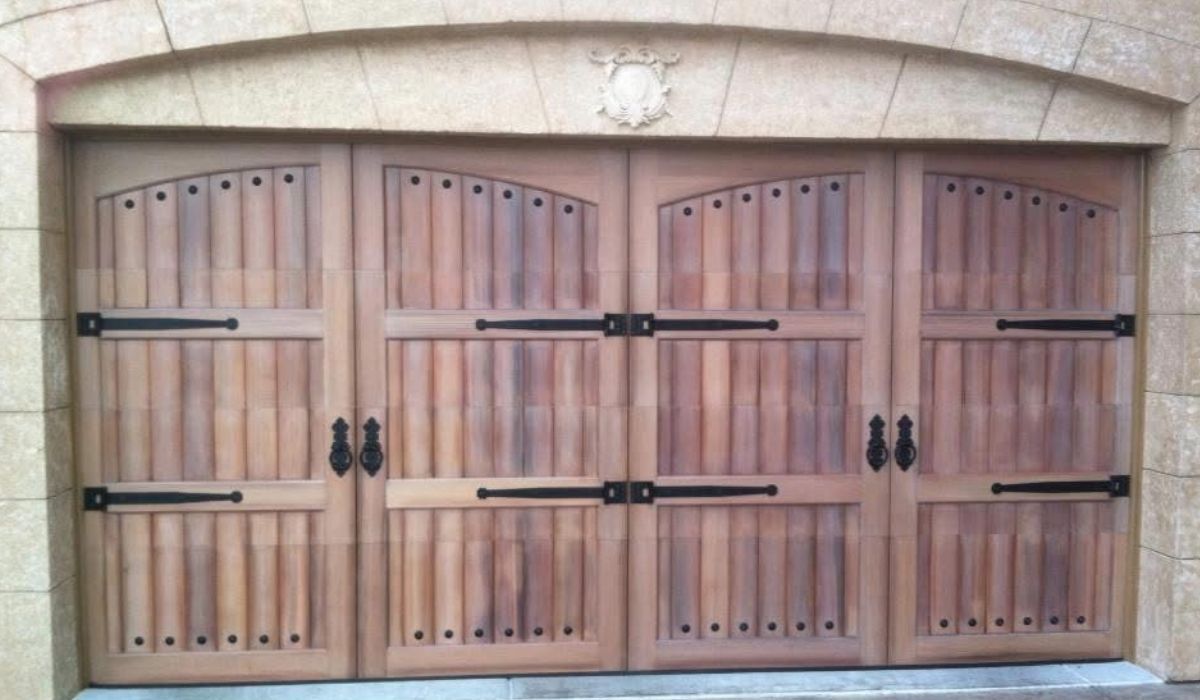 Three wooden garage doors with black hardware under a stone archway