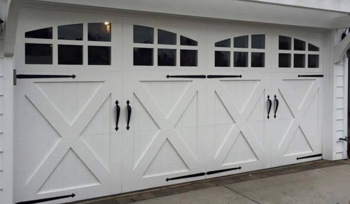 White garage doors with decorative X panels and small windows along a white building exterior
