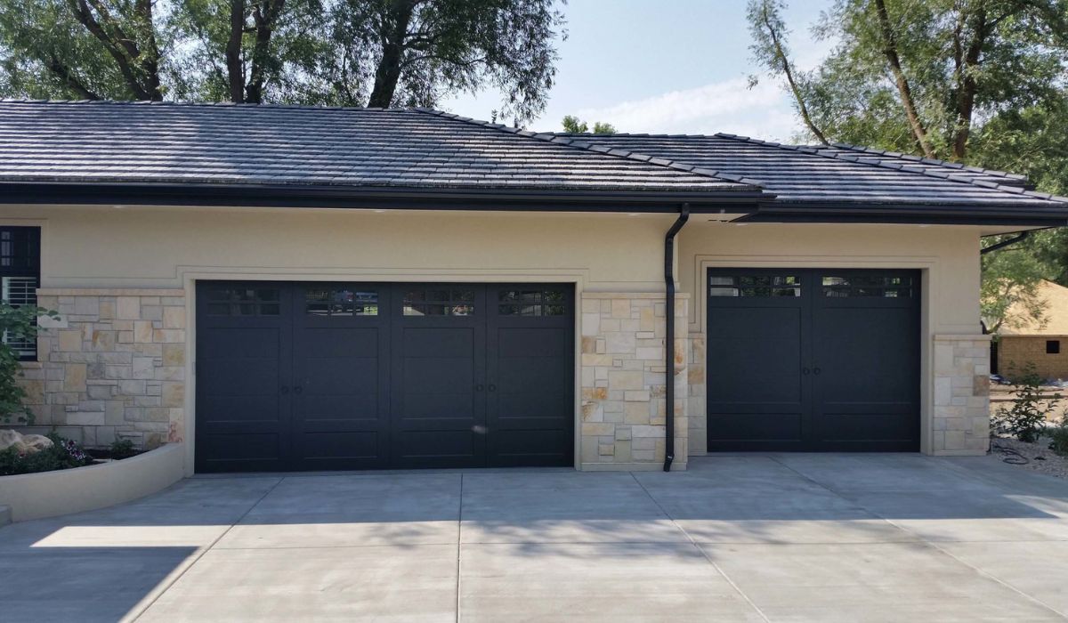 Modern single-story house exterior with two dark garage doors and a concrete driveway
