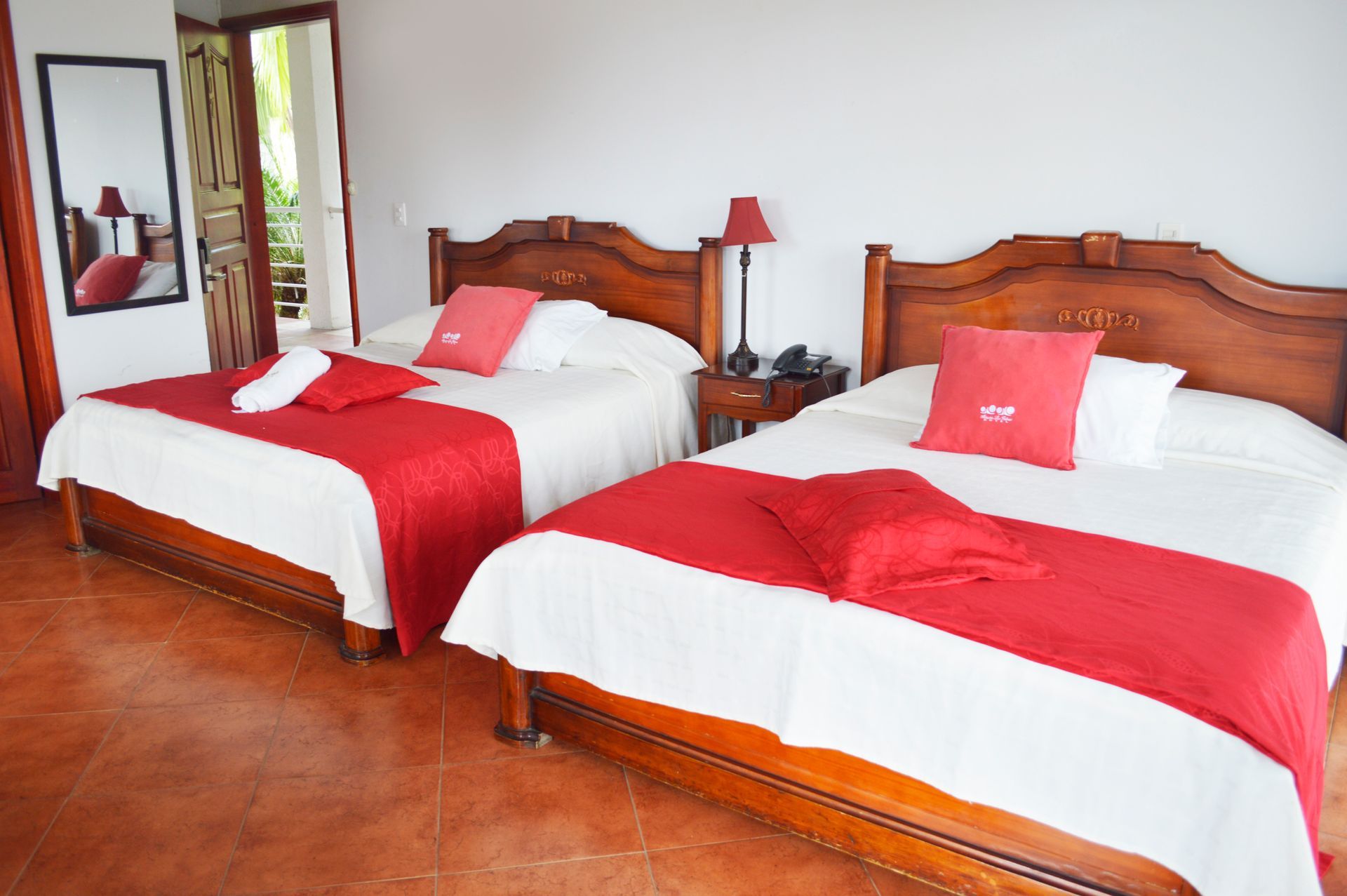 Dos camas con mantas rojas y almohadas en una habitación de hotel.