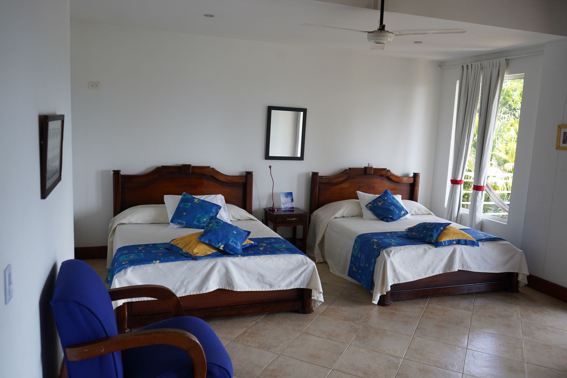 Un dormitorio con dos camas y una silla azul.