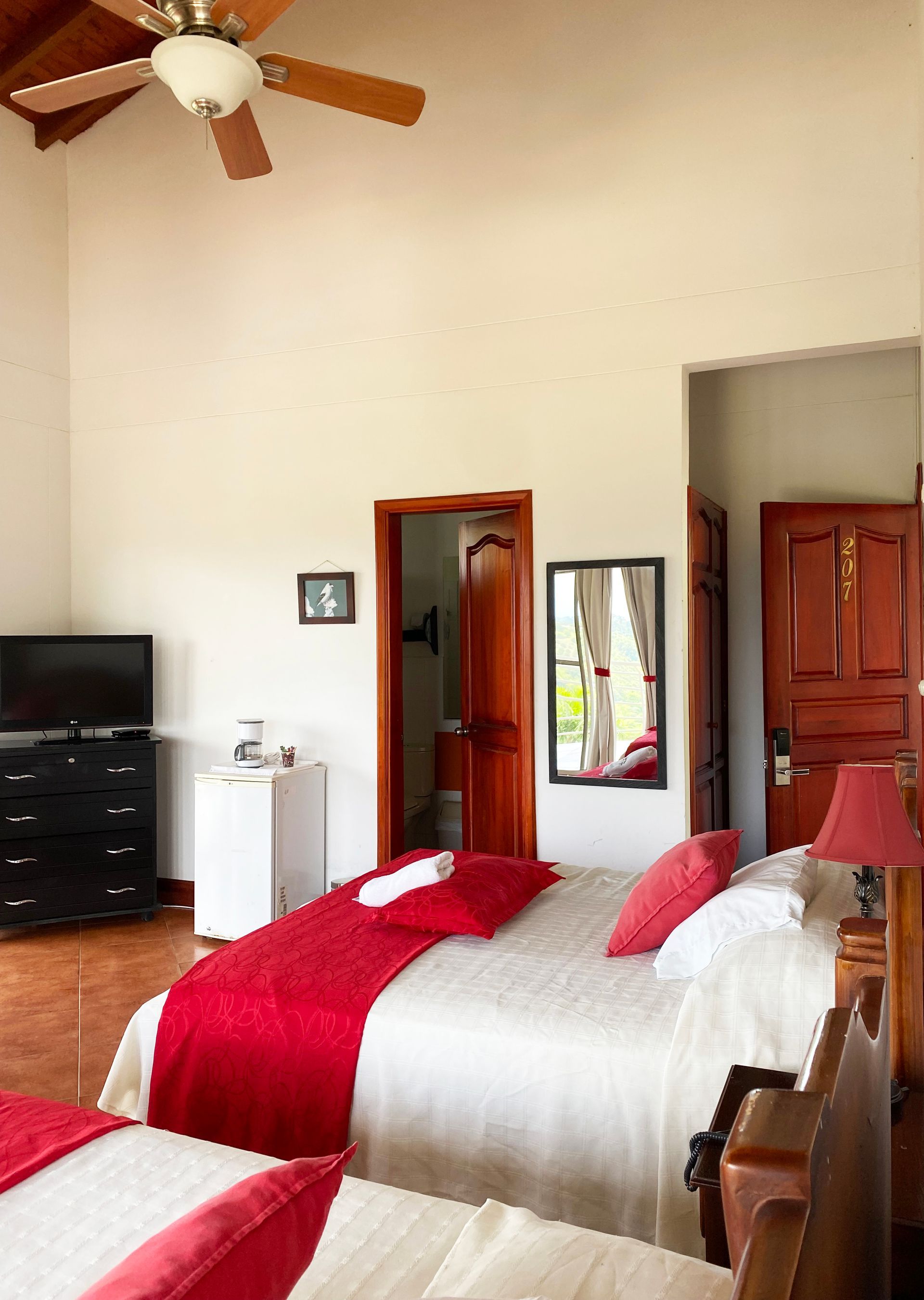 Un dormitorio con dos camas, un ventilador de techo y un televisor.