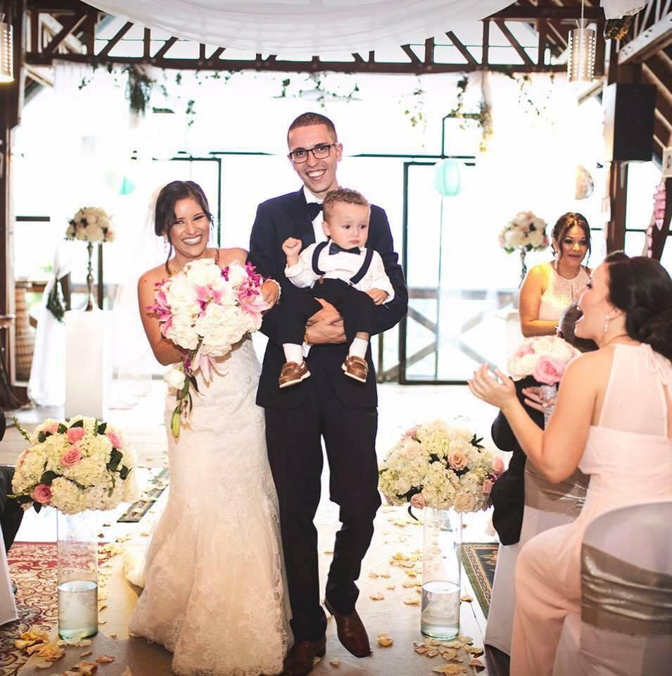 Una novia y un novio sosteniendo a un bebé en su boda