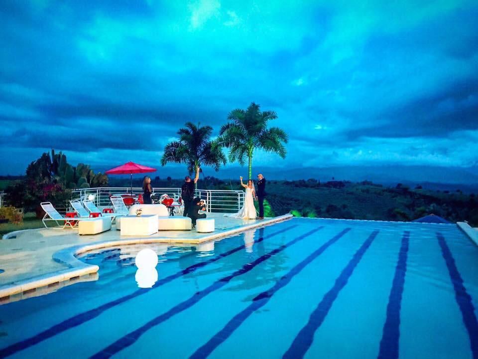 Una novia y un novio están de pie en el borde de una piscina infinita.