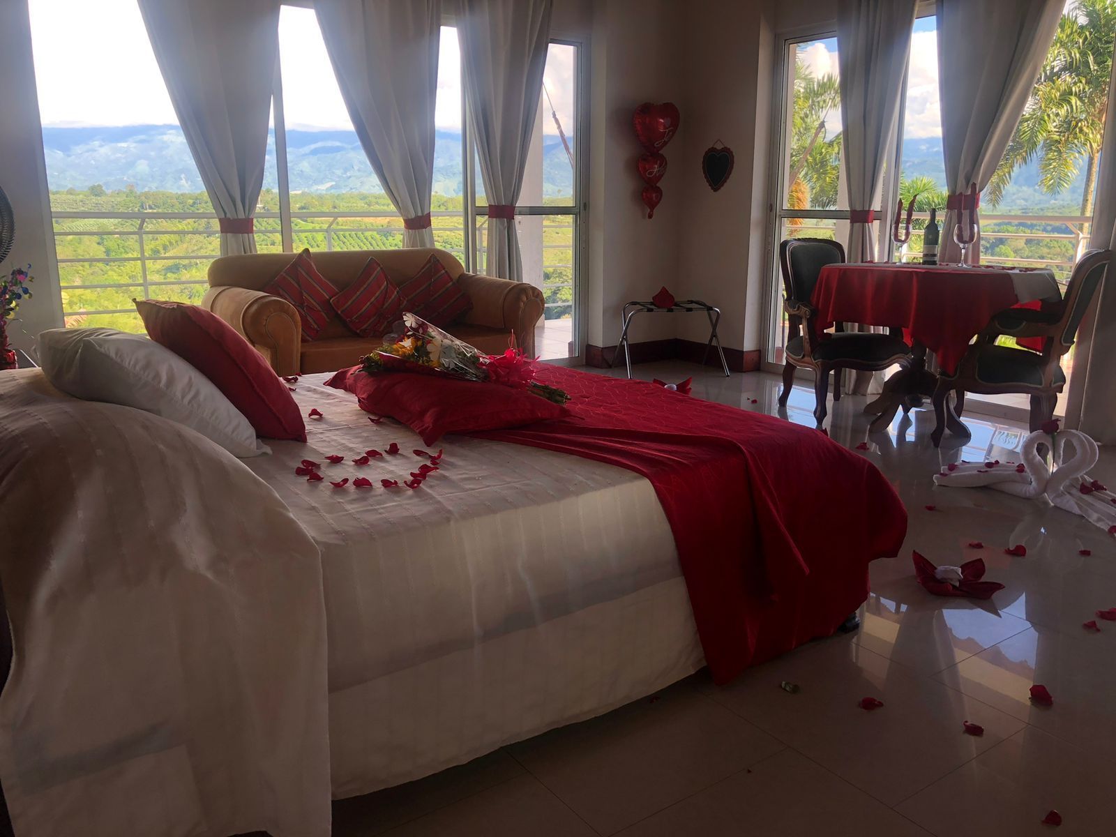 Un dormitorio con cama, sofá, mesa y sillas decorado para el día de San Valentín.