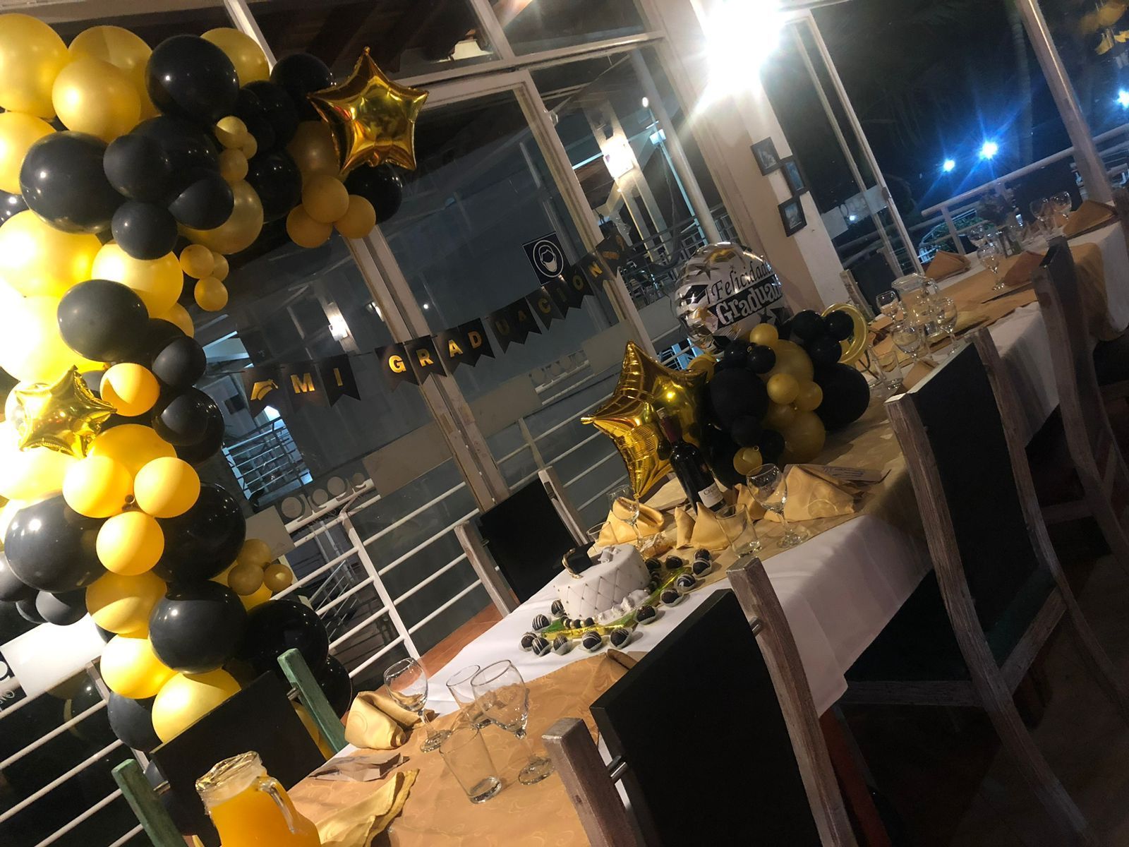 Una mesa está decorada con globos negros y dorados para una fiesta de graduación.