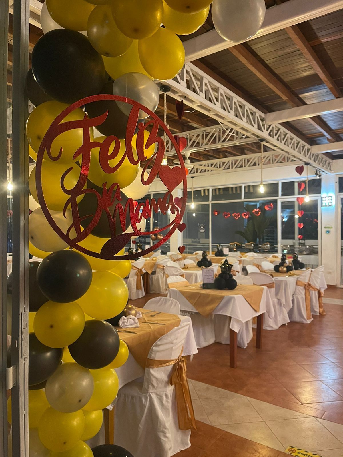 Un restaurante con mesas y sillas decoradas con globos amarillos y negros.