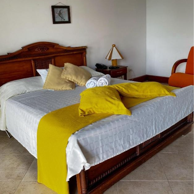 Una cama con una manta amarilla y almohadas en una habitación de hotel.