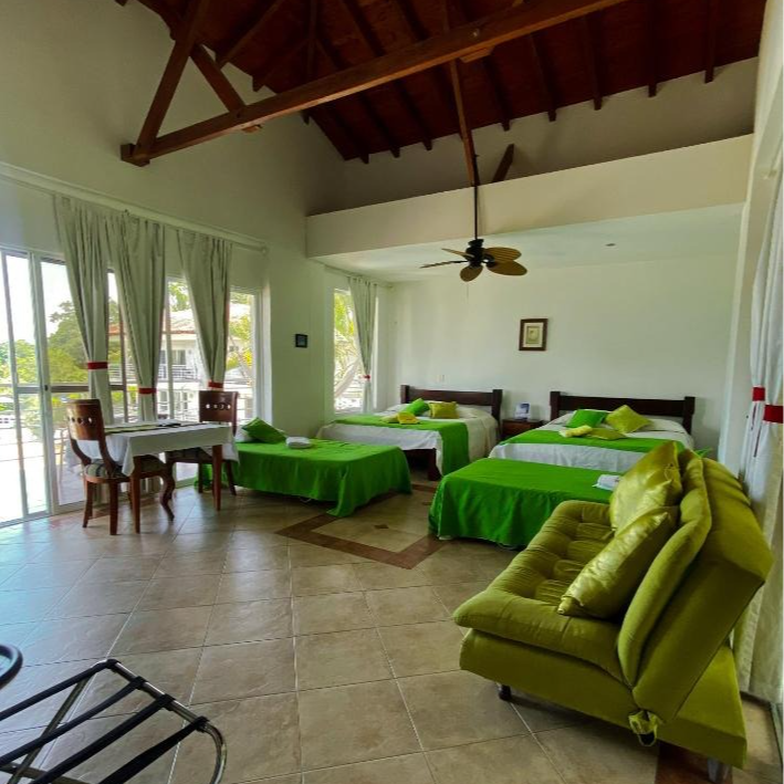 Una habitación de hotel con tres camas y un ventilador de techo.