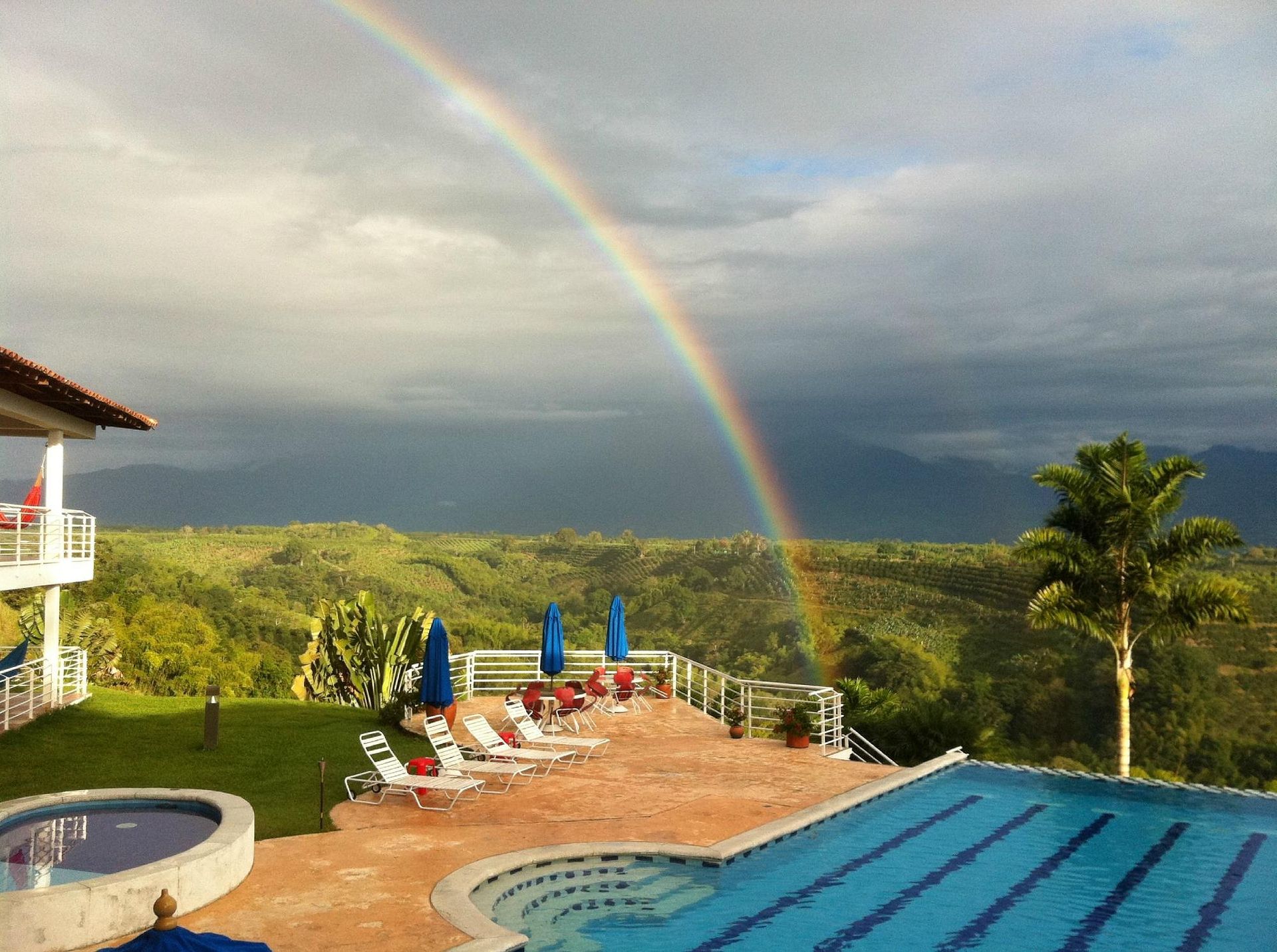 Una piscina con un arco iris en el cielo encima.