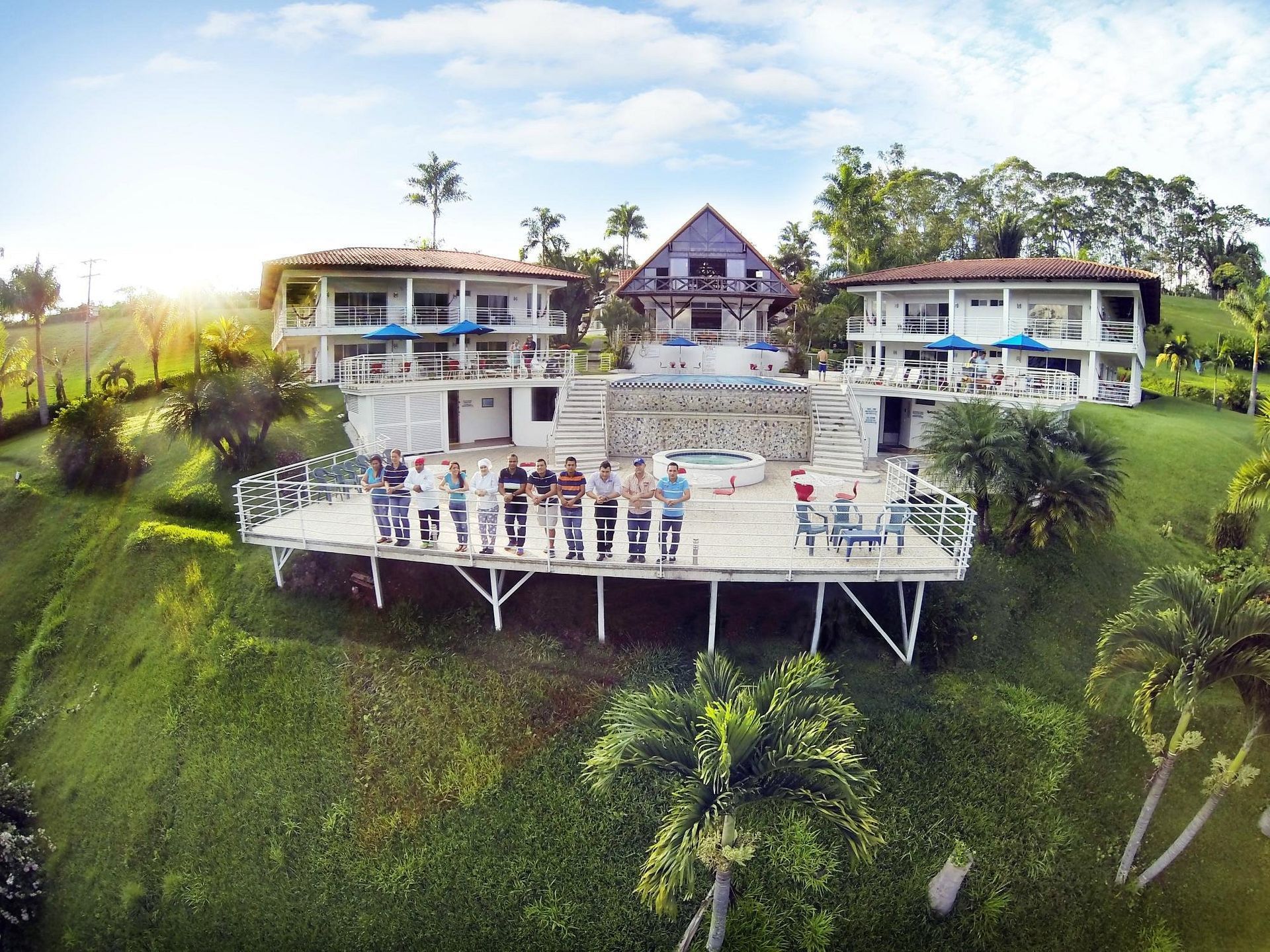 Un grupo de personas está de pie en una terraza frente a una casa grande.