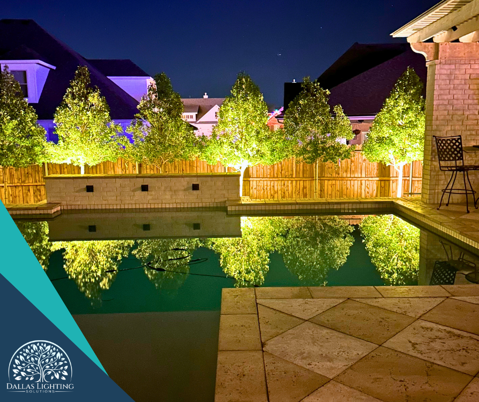 A swimming pool surrounded by trees is lit up at night