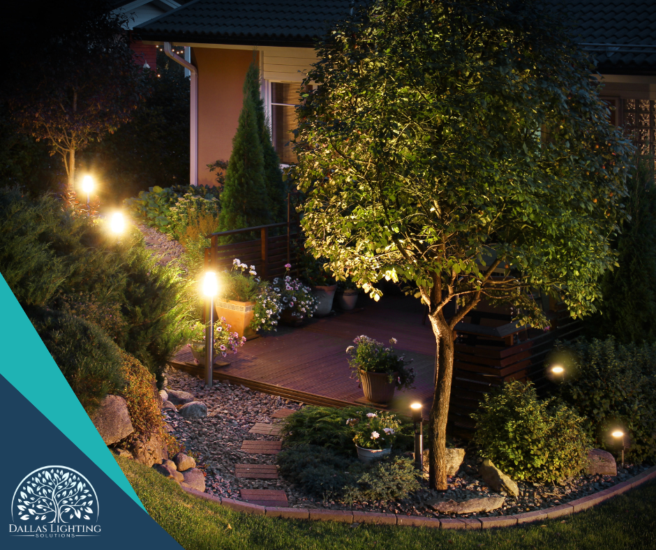 A garden with a house in the background is lit up at night