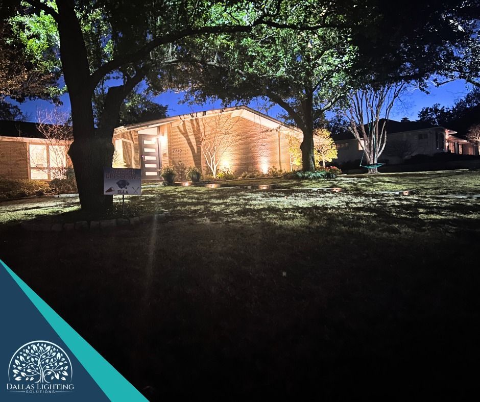 A house is lit up at night with trees in front of it