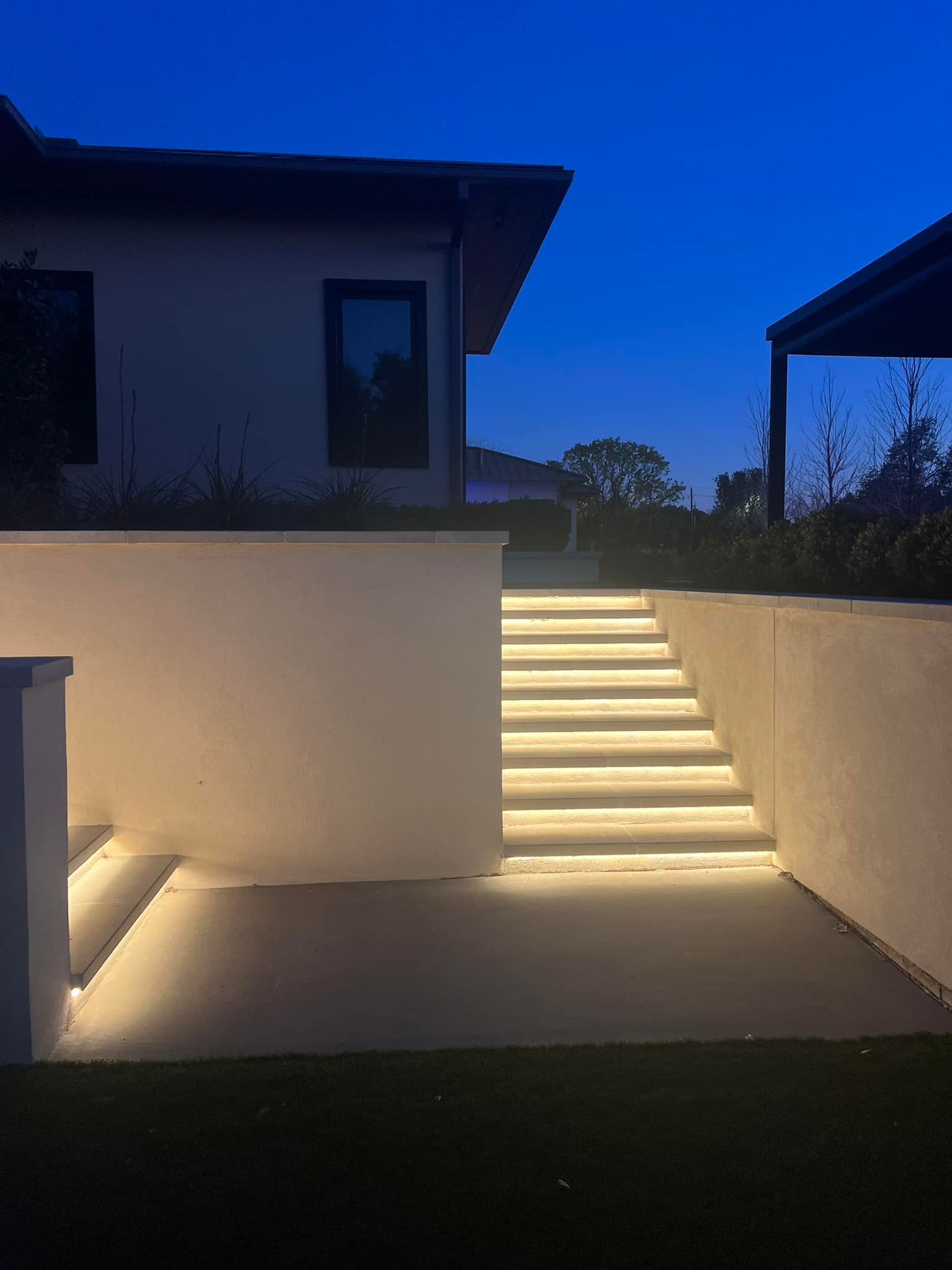 A set of stairs leading up to a house are lit up at night.