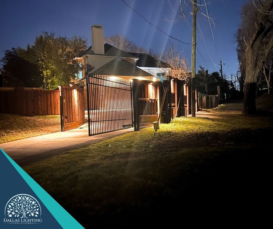 A house with a fence and a gate is lit up at night