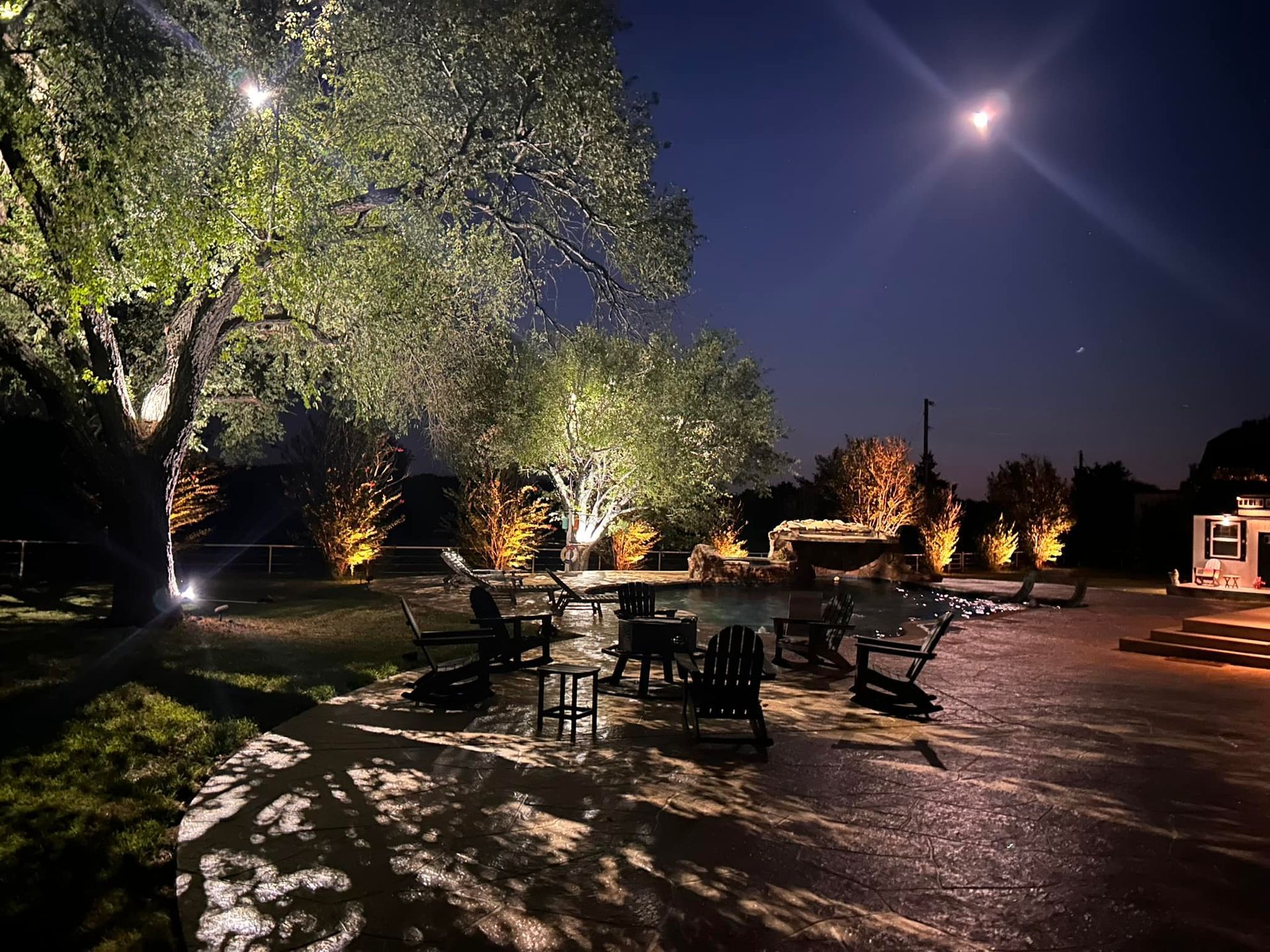 A patio area with tables and chairs is lit up at night.