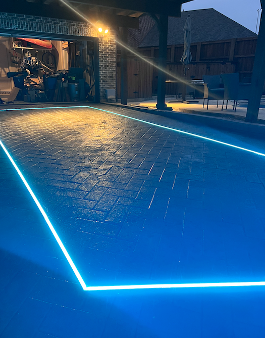 A swimming pool is lit up at night with blue lights.