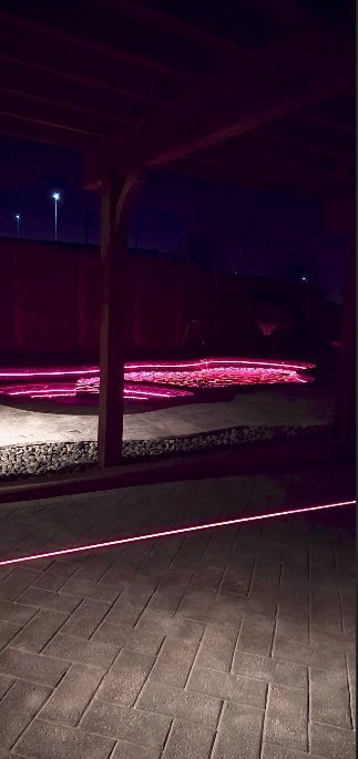 A purple light is shining on a brick walkway at night.