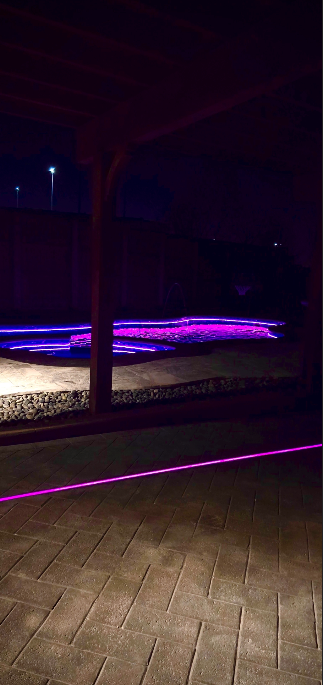 A pool is lit up at night with purple lights.