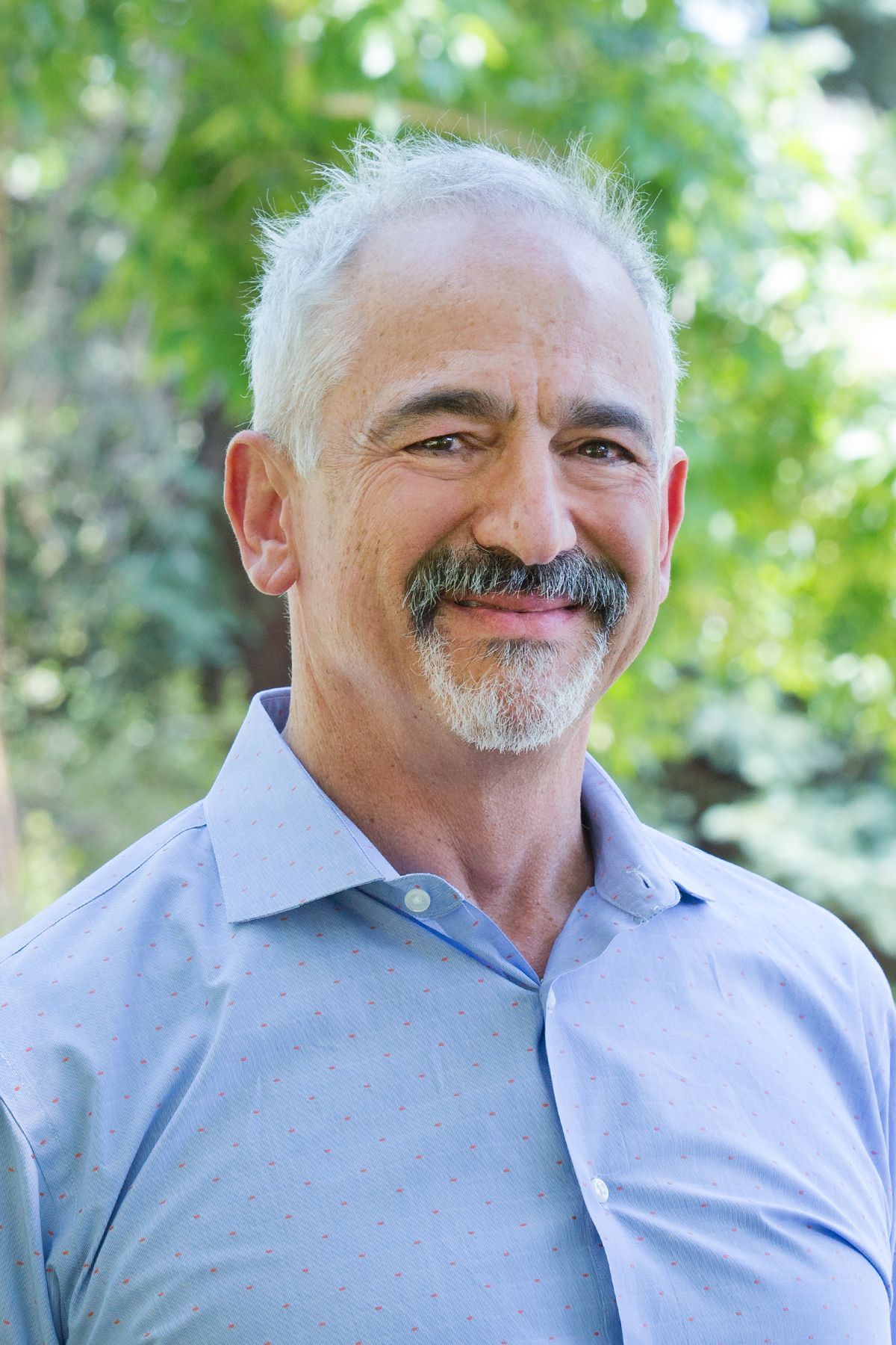 A man with a beard and mustache is smiling for the camera.