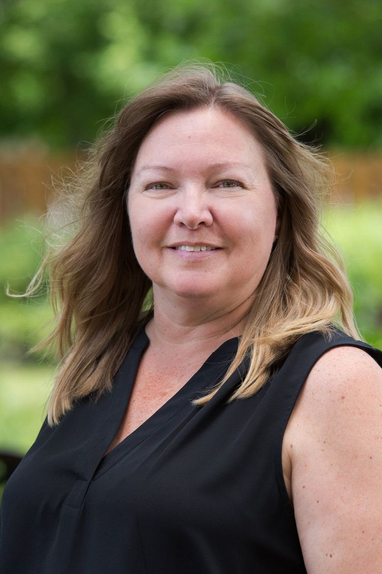 A woman in a black shirt is smiling for the camera.