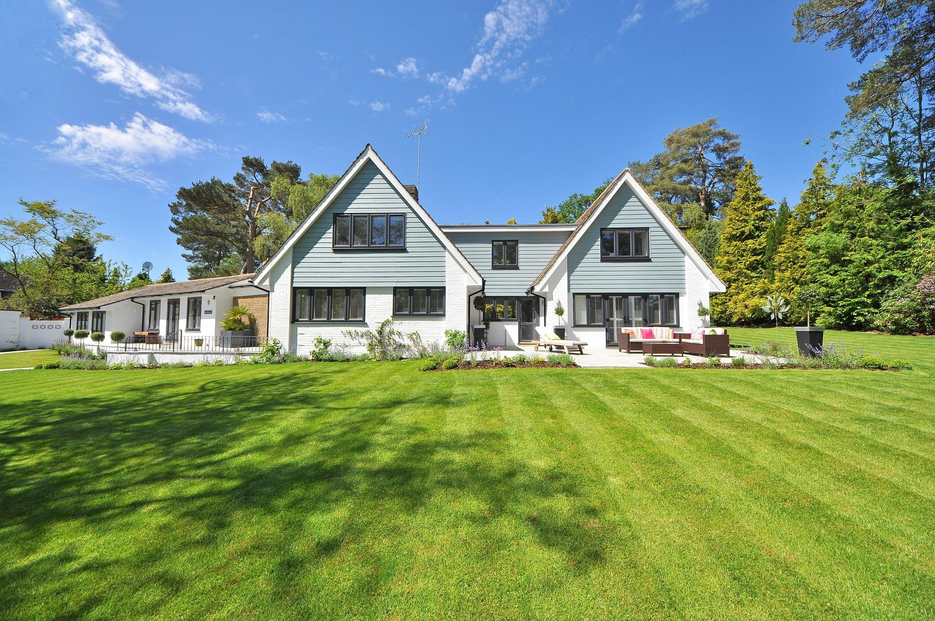 a house with a lush green lawn and a rock garden in front of it .