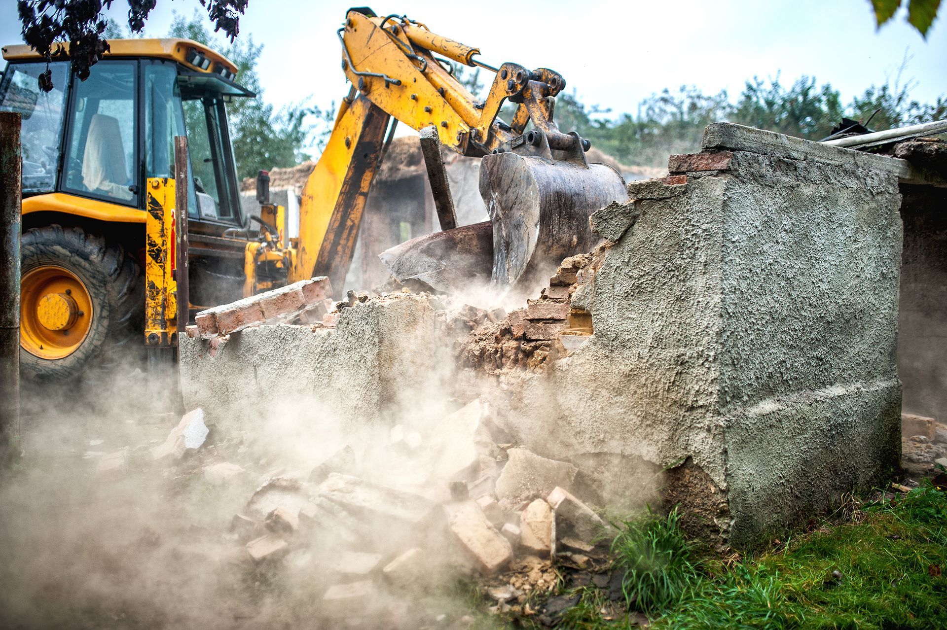 a yellow bulldozer is demolishing a building .