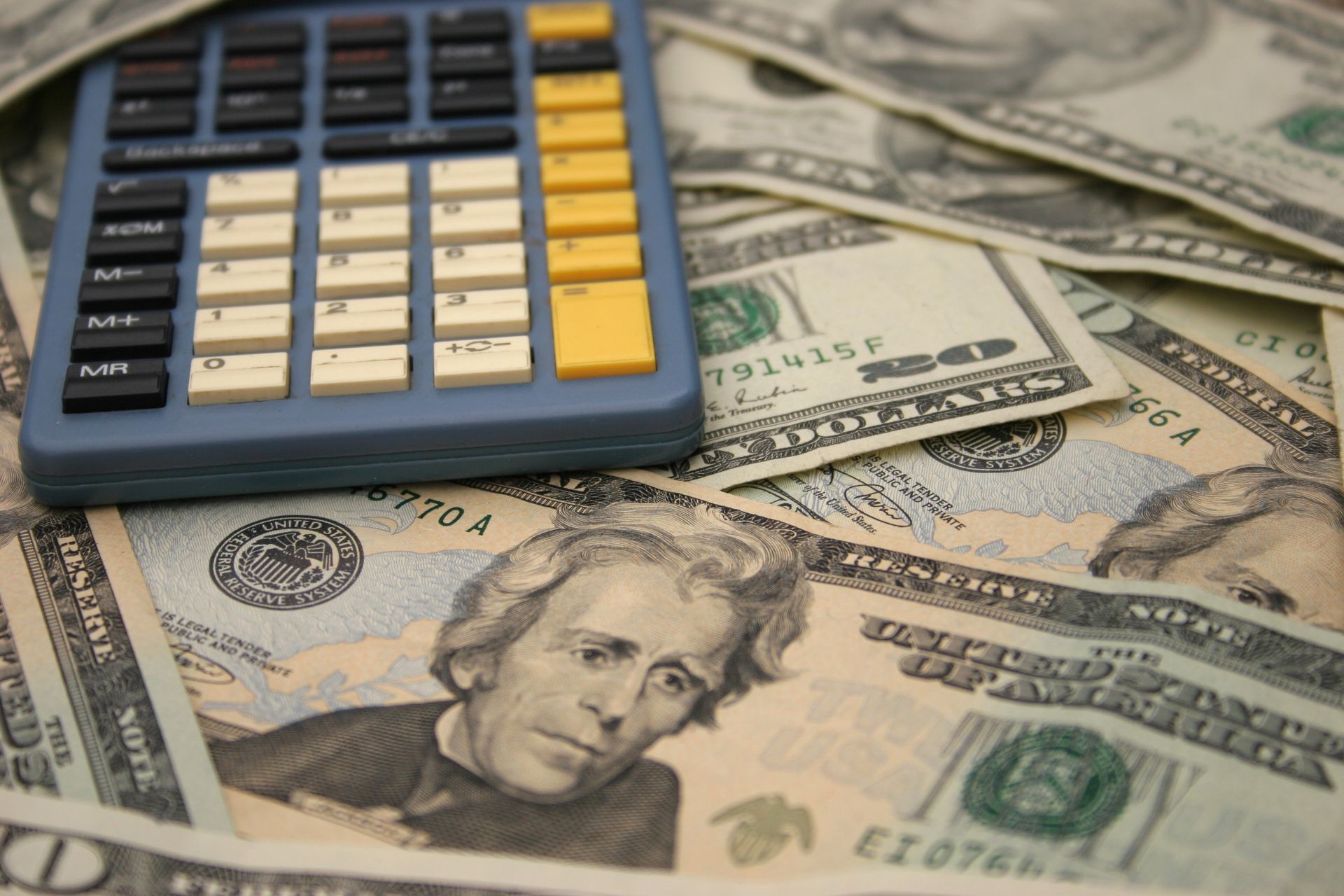Calculator on top of U.S. dollar bills, showing money and budgeting concept